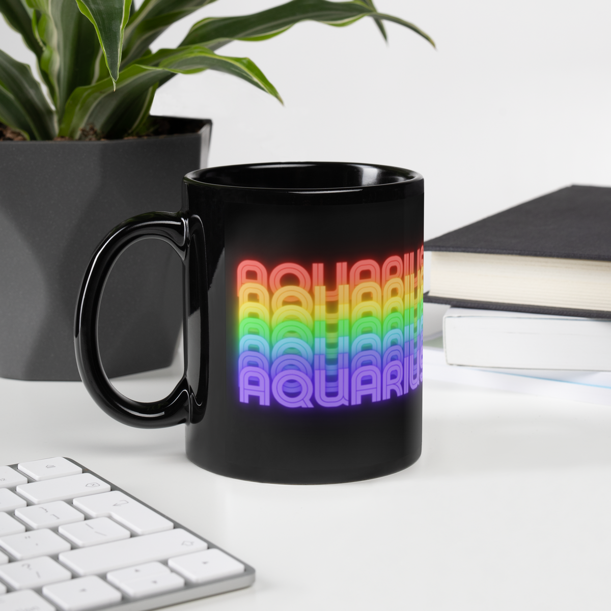Black mug with rainbow 'AQUARIUS' text on a desk with a plant and books in the background (11 oz.)