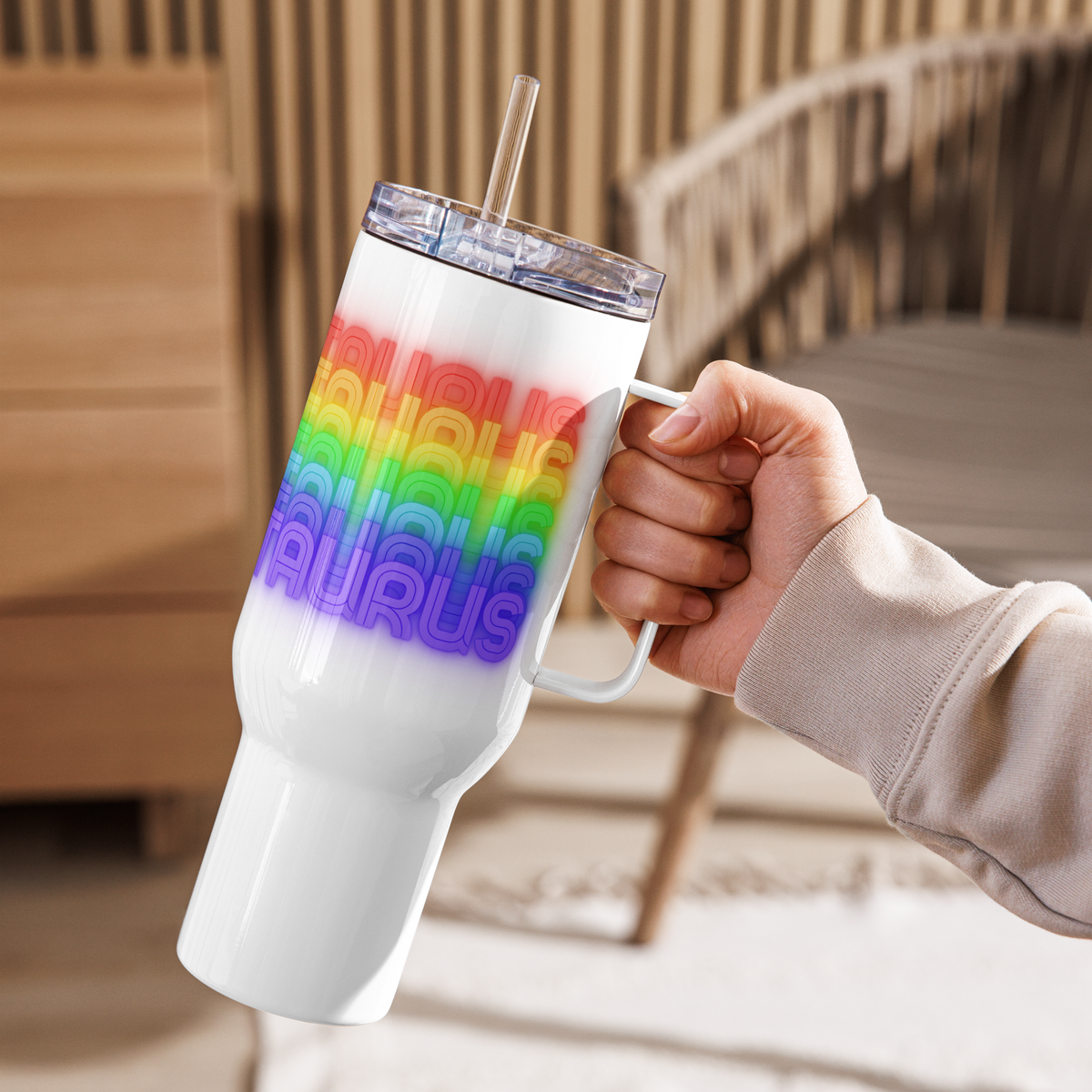 White tumbler with rainbow Taurus design pattern held by a person outdoors
