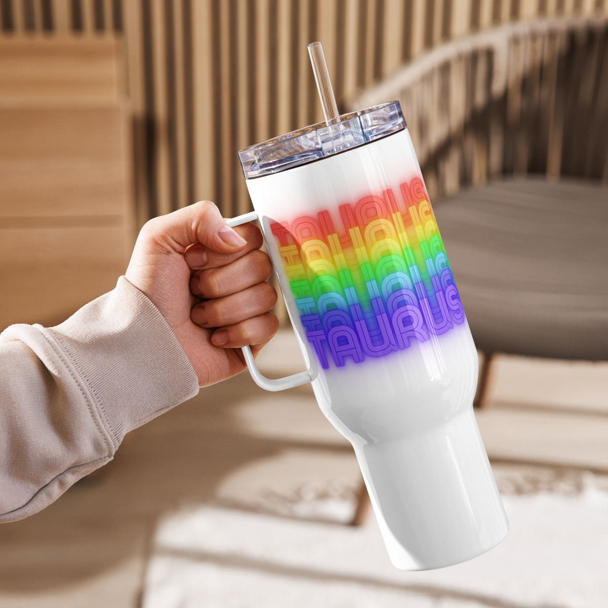 40oz. White tumbler with rainbow-colored Taurus text design held by a hand, blurred background
